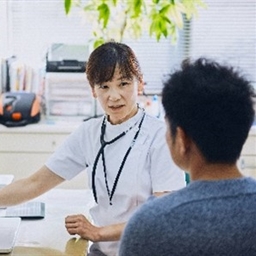 A doctor at their desk with a laptop talking to a patient